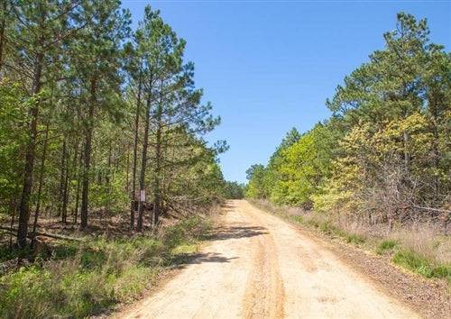 Aerial view of Eagles Nest Ranch lot 86 in Pushmataha County, Oklahoma, featuring lush land and a flowing stream in the countryside.